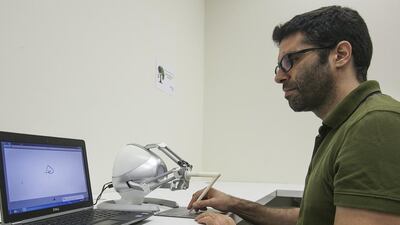 George Korres, a research engineer at New York University Abu Dhabi, demonstrates a haptic device that guides a person’s hand while they are writing in Arabic. Mona Al Marzooqi / The National