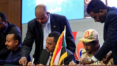 Sudan's protest leader Ahmad Rabie, left, and General Mohahmed Hamdan Dagalo sign an agreement outlining a transition to civilian rule, in Khartoum on August 17. 2019. AFP