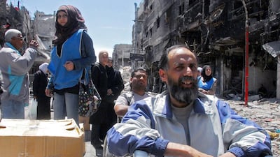A photograph released by the official Syrian Arab News Agency shows people waiting for boxes of food aid being distributed by the United Nations Relief and Works Agency in the besieged Damascus suburb of Yarmouk on April 24, 2014. AFP
