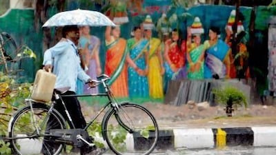 A cyclist and a pedestrian share an umbrella as they walk past a painted wall during showers in Hyderabad, India on Wednesday. The monsoon, crucial for India's agriculture, set over Kerala yesterday. Mahesh Kumar A / AP photo