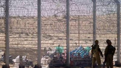 African refugees sit on the ground behind a border fence after attempting to cross illegally from Egypt into Israel.