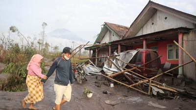 People walk near their damaged home. AP