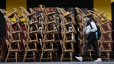 A pedestrian walks past a closed cafe terrace with chairs stacked outside in Paris, France. EPA