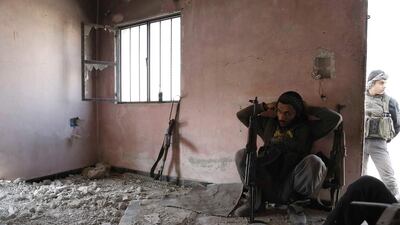 Syrian rebel fighters from the Failaq al-Rahman brigade, take a break as they hide inside a building on the frontline against regime forces in the rebel-controlled village of Bala, in the eastern Ghouta region, on the outskirts of the capital Damascus. Abdulmonam Eassa / AFP