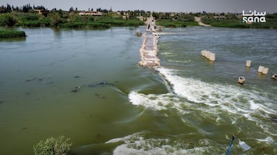 Water surges over an earthen bridge in Deir Ezzor, Syria. Sana