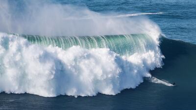 A surfer rides a wave amid a giant swell at Praia do Norte in Nazare on Thursday, October 29, 2020. AFP
