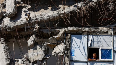 A Palestinian looks out from a window over the rubble of a building destroyed during the Israeli war, at the Jabalia refugee camp in Gaza. Reuters