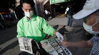 A man, right, receives an extra issue of Yomiuri newspaper in Tokyo on August 28, 2020, showing a report of Japanese Prime Minister Shinzo Abe's intention to resign due to his declining health. Hiro Komae / AP