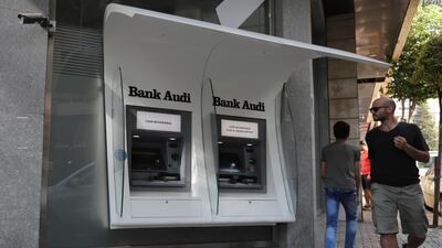 People pass by an out of service ATM machines at a closed bank in the Lebanese capital Beirut. AP