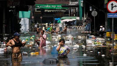 People wade through floodwaters during an evacuation from a flooded market in Bangkok October 24, 2011. More districts of Thailand's capital were on high alert on Monday with floods bearing down from northern Bangkok and authorities faced a race against t???