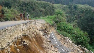 Locals stand next to a damaged road near Mendi in Papua New Guinea's highlands region on February 27, 2018, a day after a 7.5-magnitude earthquake struck the area. Melvin Levongo / AFP