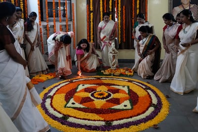 Women light lamps around a floral pookalam motif during festivities marking Onam in Hyderabad. AP