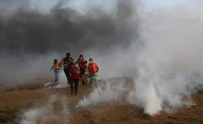 Medics evacuate a wounded youth in the middle of teargas fired by Israeli troops. AP