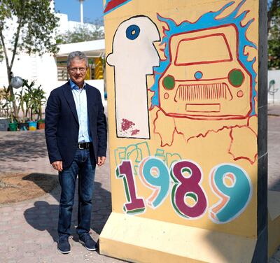 Frank Michaelis in front of a Berlin wall artwork at German International School, Abu Dhabi. Mr Michaelis lived in East Germany at the time the wall fell. Victor Besa / The National