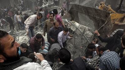Syrians try to remove large pieces of concrete with the help of a tractor to free those trapped under the rubble following an air strike by government forces on that destroyed two five-storey apartment blocks and severely damaged several buildings in a residential neighbourhood of the northern city of Aleppo, Syria. Victor Breiner / AFP