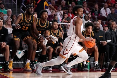 Southern California guard Bronny James, dribbles as members of Long Beach State watch from the bench. AP