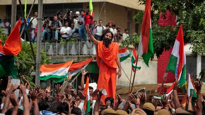 August 17, 2011: Indian yoga guru Baba Ramdev, center, waves to supporters of India's most prominent anti-corruption crusader Anna Hazare as they gather in a show of support outside the Tihar prison complex where Hazare is holding his hunger strike in New???