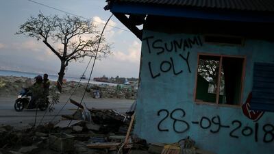 Motorists ride past a building damaged the tsunami in Loli Tasiburi village. AP Photo