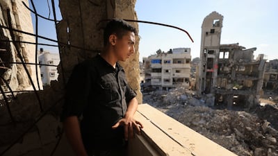 A Palestinian young man looks out of a window at the rubble of residential buildings destroyed during the war, in Gaza City, on September 28, 2026. Reuters
