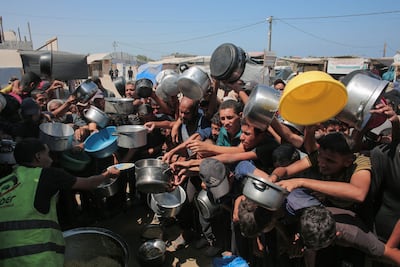 Palestinians rush to receive food portions from a charity kitchen in Khan Younis. AFP