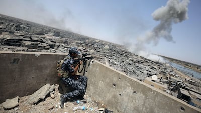 TOPSHOT - An Iraqi forces sniper looks on as smoke billows, following an airstrike by US-led international coalition forces targeting Islamic State (IS) group, in the Old City of Mosul on July 9, 2017, as their part of the battle has been declared accomplished, while other forces continue to fight Islamic State (IS) jihadists in the city. Iraq will announce imminently a final victory in the nearly nine-month offensive to retake Mosul from jihadists, a US general said Saturday, as celebrations broke out among police forces in the city. / AFP PHOTO / Ahmad al-Rubaye