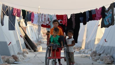 Syrian children push a boy in a makeshift wheelchair at a displacement camp in Idlib. AFP