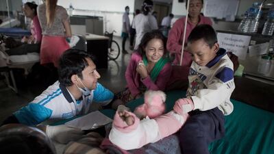 A Nepalese staff member of Handicap International (L) speaks to Dinesh Tamang, 10, as he sits on his bed at the National Trauma Centre hospital in the capital Kathmandu on April 30, 2015, following a 7.8 magnitude earthquake which struck the Himalayan nation on April 25. The UN launched an appeal for Nepalese quake survivors in dire need of shelter, food and medical care April 30 as anger boiled at the government’s inability to cope with a disaster that has killed more than 5,000 people. Nicolas Asfouri / AFP