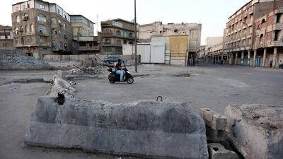 A man rides his motorcycle next to concrete blocks erected by Iraqi security forces to close a district as a part of restrictions against the spread of Covid-19 in central Baghdad, Iraq. EPA