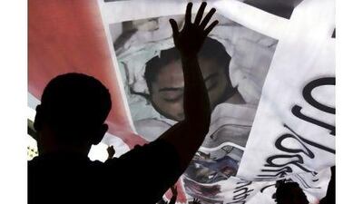 Protesters hold up a banner bearing photographs of those who have been killed in demonstrations in Manama.