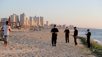 Palestinian police officers speak with a man as they patrol at a beach during a lockdown. Reuters