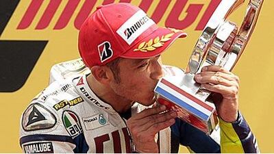 Valentino Rossi kisses his 100th grand prix winner's trophy after taking the checkered flag at the Dutch TT yesterday.