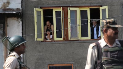 Kashmiris look from the windows of their home as Indian paramilitary soldiers stand guard near barbed wire during restrictions in the downtown area of Srinagar, the summer capital of Indian-controlled Kashmir, on July 8, 2017. Farooq Khan / EPA