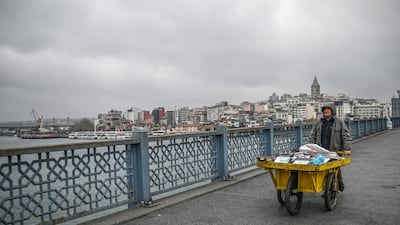 A garbage collector pushes a wheelbarrow across the empty Galata bridge in Istanbul, after Turkish officials have repeatedly urged citizens to stay home and respect social distancing rules. AFP