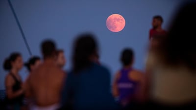 A partial lunar eclipse is visible as men and women take part in a yoga session in front of the Mediterranean sea in Barcelona, Spain. AP Photo/Emilio Morenatti