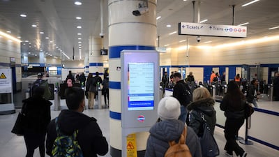 Commuters check a screen announcing service disruption at Stratford Station in London. AFP
