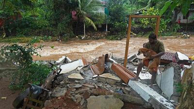 A resident with his dog amid the debris of his ruined home, as floodwater flows past. The Indian Army and Indian Air Force have joined the rescue effort in some of the worst-hit areas. AFP