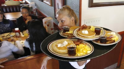 A Denny's employee carries a tray with free Grand Slam breakfasts for customers. The eaterie is heading to the Middle East. AP Photo/Alan Diaz