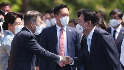 Mr Yoon shakes hands with former president Moon Jae-in upon his arrival at the ceremony. AFP