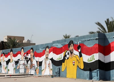 A volunteer in Baghdad paints a mural of players, fans and the Iraqi flag. Reuters