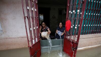 Women empty water from a house after heavy rain in Ahmedabad, India, on July 11. Reuters