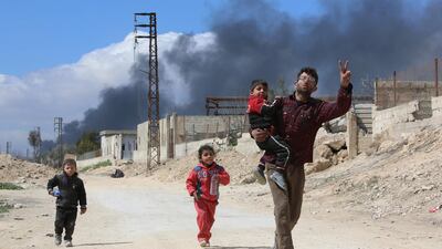 A man and his children walk towards government-held territory in Hamouria on March 16, 2018. AFP
