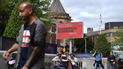 Pedestrians walk past an electronic board displaying information relating to a 'variant of concern in the area' in Blackburn, north-west England. AFP