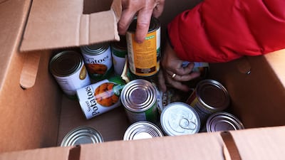 A woman looks through a box of canned food during a Thanksgiving food distribution event at Food Bank For New York City in Harlem. AFP