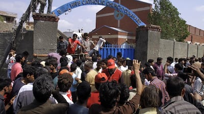 Pakistani Christians and rescue workers gather outside a church damaged from a suicide bomb attack in Lahore, Pakistan on March 15, 2015. KM Chaudary/AP Photo
