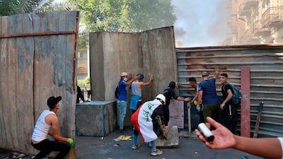 A protester shows an empty tear gas canister while protesters setting barriers during clashes between Iraqi security forces and anti-government protesters in the al-Rasheed street in Baghdad. AP Photo