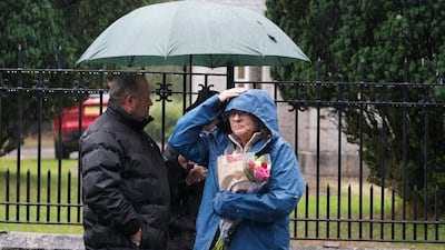 A woman holds flowers at the gates of Balmoral in Scotland, where the Queen is under medical supervision. PA