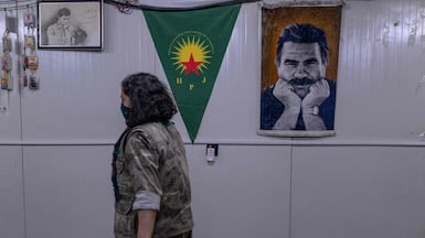 A member of the Iranian-Kurdish armed group, the Kurdistan Free Life Party (PJAK), passes a poster of Turkish-Kurdish politician Abdullah Ocalan on the Iraqi border with Iran. AFP
