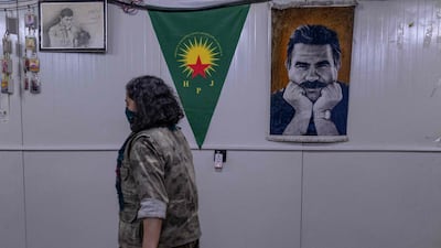 A member of the Iranian-Kurdish armed group, the Kurdistan Free Life Party (PJAK), passes a poster of Turkish-Kurdish politician Abdullah Ocalan on the Iraqi border with Iran. AFP
