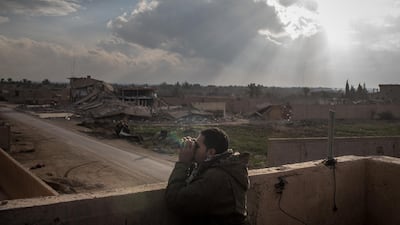 An SDF commander looks for ISIS positions from a rooftop near the front line in Bagouz, Syria. Getty Images