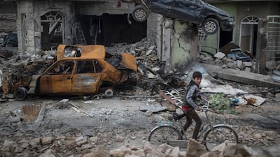 In this March 19, 2017, file photo, a boy rides his bike past destroyed cars and houses in a neighborhood liberated by Iraqi security forces on the western side of Mosul. Felipe Dana / AP